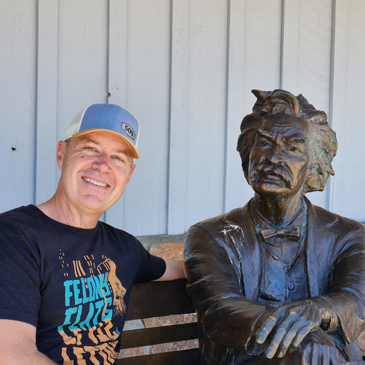 Colin Conway sitting with Mark Twain statue in Jackson, Wyoming